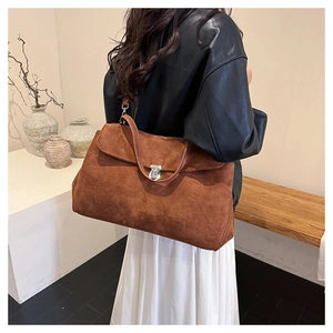 Macro shot of large brown suede shoulder bag featuring a silver metal magnetic buckle