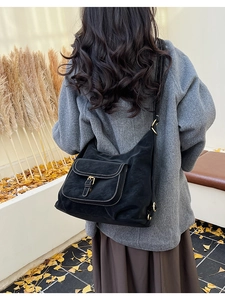 Détail du sac bandoulière vintage noir avec surpiqûres blanches et poche à boucle métal