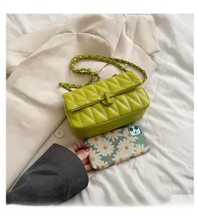 Detailed top view of the green quilted handbag with chain strap next to a phone for size