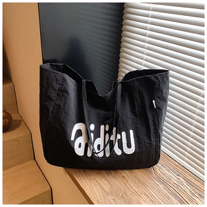 Gros plan d'un grand sac cabas noir texturé avec lettrage aiditu sur des marches