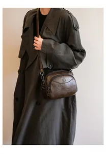 Detail of vintage brown soft leather crossbody bag with multiple zip pockets on a model