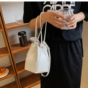 White geometric folding bucket bag shown on model with adjustable strap detail