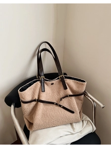 Detail view of large sherpa fleece tote bag with brown leather straps on a chair