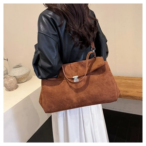 Detailed view of brown suede shoulder bag with silver buckle and minimalist design