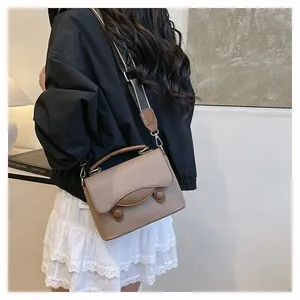 Vue latérale d'un sac bandoulière vintage marron avec large sangle sur un mannequin