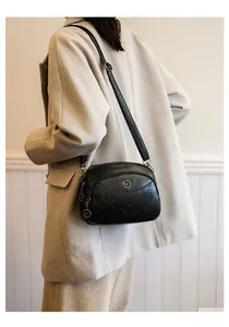 Detail of soft black faux leather crossbody bag with multiple zipper layers and metal decor