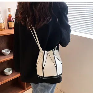 Detail of geometric folding bucket bag with black trim on white faux leather