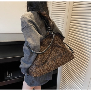 Detail der großen Leopard-Print-Einkaufstasche mit schwarzen Lederriemen am Modell