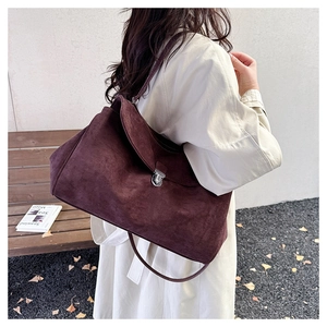 Close-up of dark brown suede tote bag featuring a silver metal twist lock and flap design