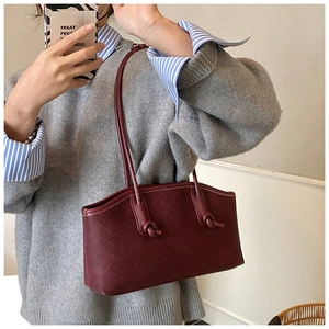 Close-up of woven wine red leather handbag texture and decorative strap knots