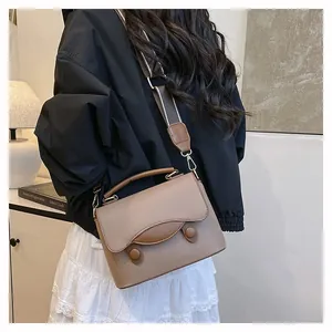 Détail du sac en cuir marron clair avec large bandoulière rayée et ferrures dorées