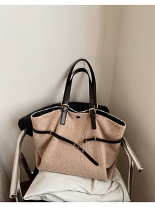 Detailed close-up of beige plush tote bag texture with brown leather straps and gold buckle