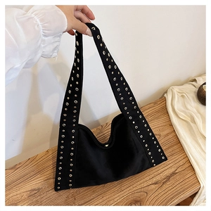 Detail of black velvet shoulder bag featuring punk style wide strap with gold metal eyelets