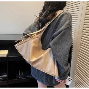 Detail van minimalistische beige hobo-tas met zacht kunstleer en brede schouderband