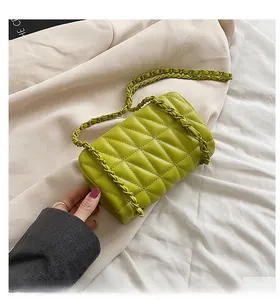 Macro shot of grass green quilted handbag featuring elegant diamond stitching and chain strap