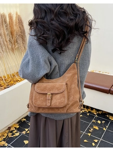 Gros plan d'un sac cabas en daim marron avec boucle réglable porté par un mannequin
