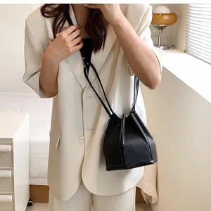 Detail view of a black drawstring bucket bag with geometric hexagonal bottom on a model