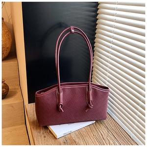 Detailed texture of burgundy woven leather tote bag with elegant shadow lighting