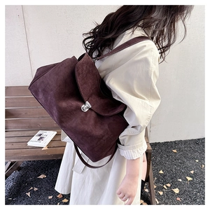 Close-up of matte suede shoulder bag featuring a vintage silver metal buckle closure