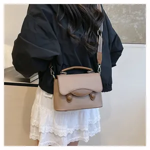 Détail du sac en cuir marron à motif litchi avec rabat courbé et bandoulière large