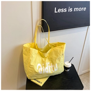 Détail d'un grand sac fourre-tout jaune vif avec logo Aiditu sur une table basse