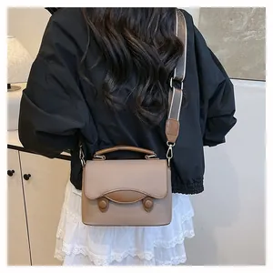 Sac bandoulière en cuir grainé marron clair avec sangle rayée et détails dorés