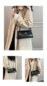 Detail of black glossy pebbled leather envelope bag with vintage gold ring buckle and strap