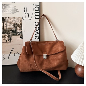 Detail of vintage brown suede shoulder bag with metallic buckle and retro matte texture