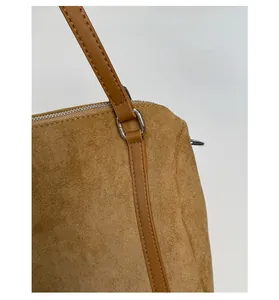 Detail of brown faux suede shoulder bag featuring leather patchwork and silver hardware