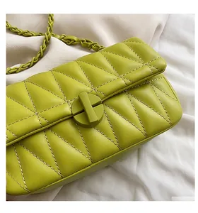 Detail of lime green quilted handbag featuring a swivel lock and woven chain strap