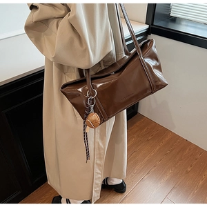 Detail shot of gloss oil wax leather tote bag featuring a cute cookie shape bag charm