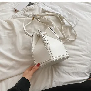 Detail view of the white geometric folding bucket bag with adjustable shoulder strap