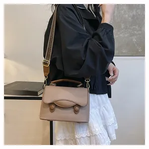 Détail d'un sac à main en cuir kaki avec grain de litchi et bandoulière tissée