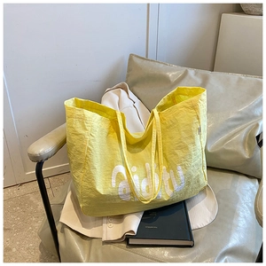 Gros plan du sac cabas en nylon plissé jaune avec logo aiditu sur une chaise chic