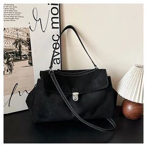 Detail of minimalist suede shoulder bag featuring silver metal lock and white contrast stitching