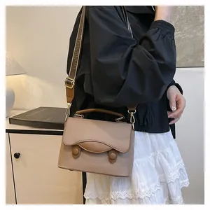 Détail d'un sac bandoulière beige vintage avec bordure brune et sangle jacquard