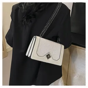 Detail showing faux snakeskin texture, metal chain strap, and lock on cream crossbody bag