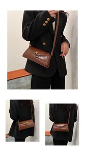 Detail of dark brown glossy leather crossbody bag with vintage brass circular buckle