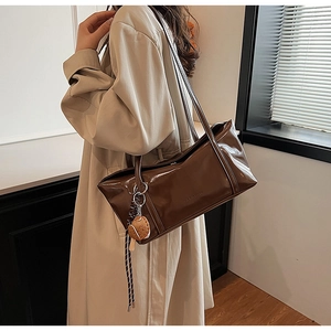 Detail of dark brown patent leather tote with creative burger charm and long tassel accent
