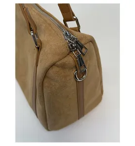 Detail of premium brown suede handbag featuring dual silver zippers and metal ring buckles