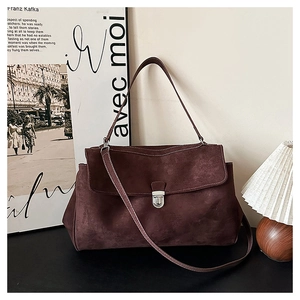 Close-up of retro suede shoulder bag featuring a silver metal buckle and soft matte texture