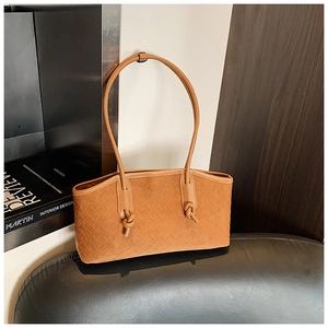 Detail of brown woven faux leather tote bag with elegant knot detail on the shoulder strap