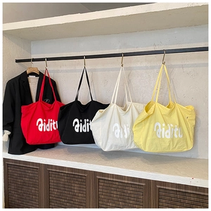 Vue détaillée de grands sacs cabas en toile en quatre couleurs sur un présentoir de magasin