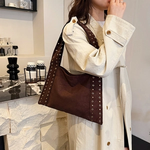 Brown velvet shoulder bag with metallic grommets shown on model in a cafe setting