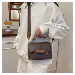 Détail d'un sac à main en cuir marron avec rabat contrasté et bandoulière en jacquard