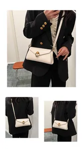 Detail of creamy white leather crossbody bag with distinctive gold circular ring buckle