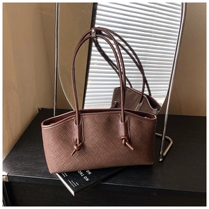 Detailed view of brown woven leather tote with intricate texture and tied straps