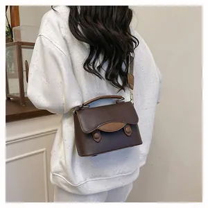 Vue détaillée du sac à main en cuir marron foncé texturé porté par un mannequin