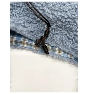Detailed close-up of blue sherpa fleece fabric with plaid trim and woven drawstring