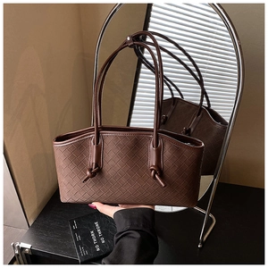 Detail of dark brown woven leather texture on a large tote bag with knotted strap handle